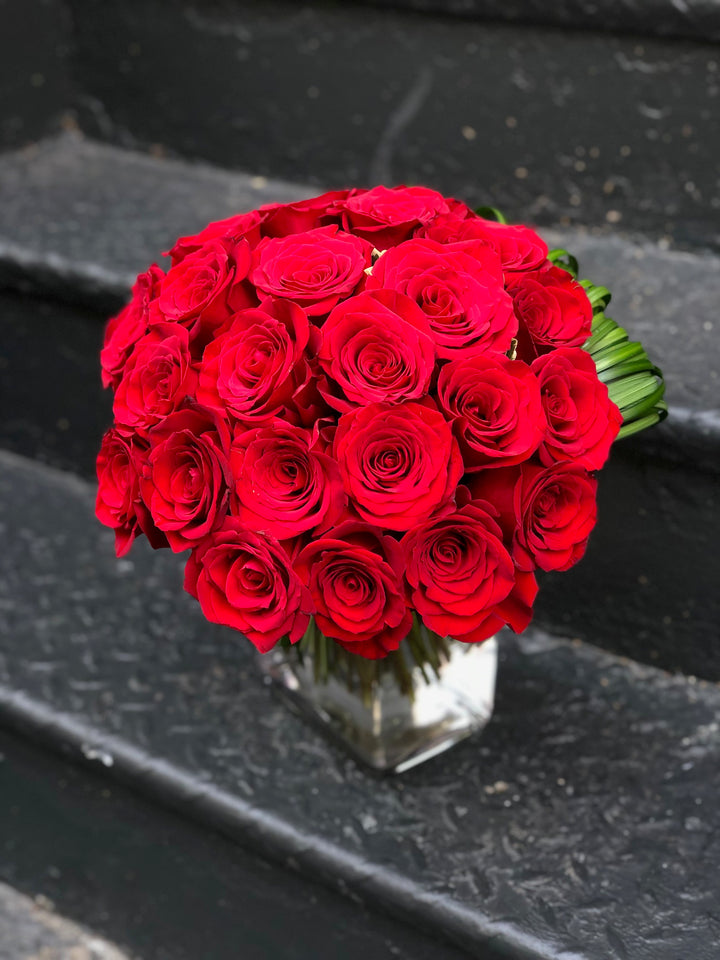 A Bouquet Style Rose Arrangement with Accents of Green Modern Leaf work and a succulent.